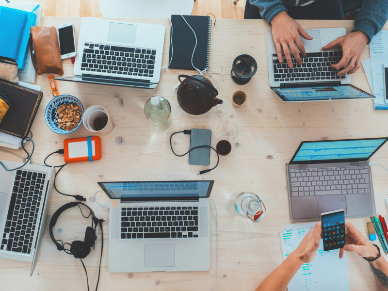 People working off of several different tech products, laptops, phones