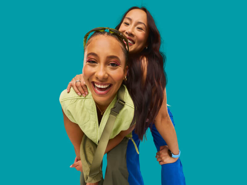 Two women laughing joyfully with a teal EE colour background