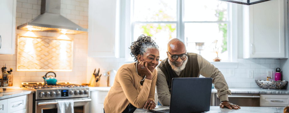 Couple using a laptop together at home in the kitchen