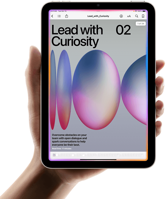 A user holds iPad mini in portrait view in one hand. The screen displays the Books app