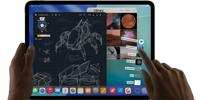 iPad Pro, space black colour, left hand holding device, right hand pointing gesturing to manipulate multiple open app windows, a drawing app with sketches of mechanical designs, photos library of planets and space images, downloads folder files fanned out