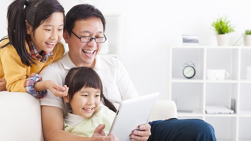 Dad and two children looking at a tablet screen