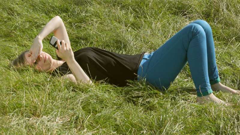 Woman with phone lying on grass