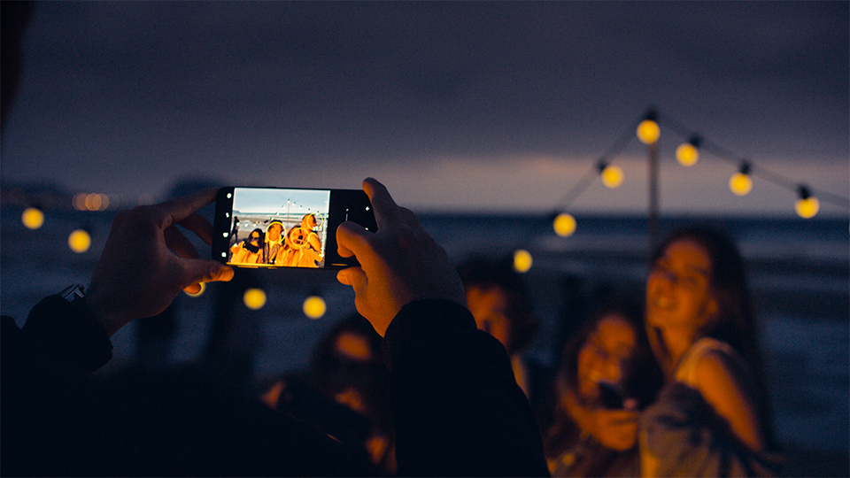 someone taking a group shot at night time on their mobile phone