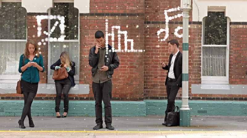 Various people using their smartphones while waiting for a bus