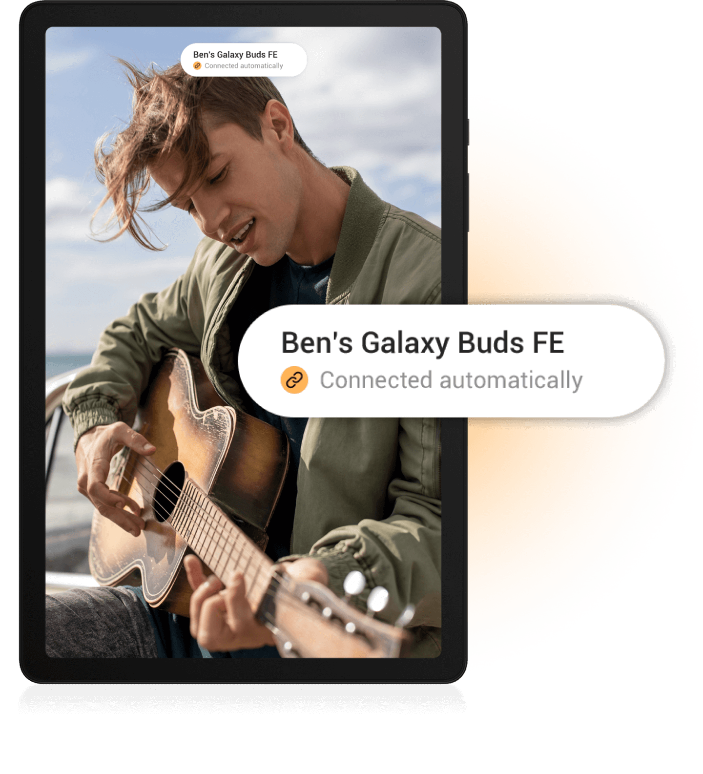 A young male playing an acousting guitar wearing a green khaki jacket.