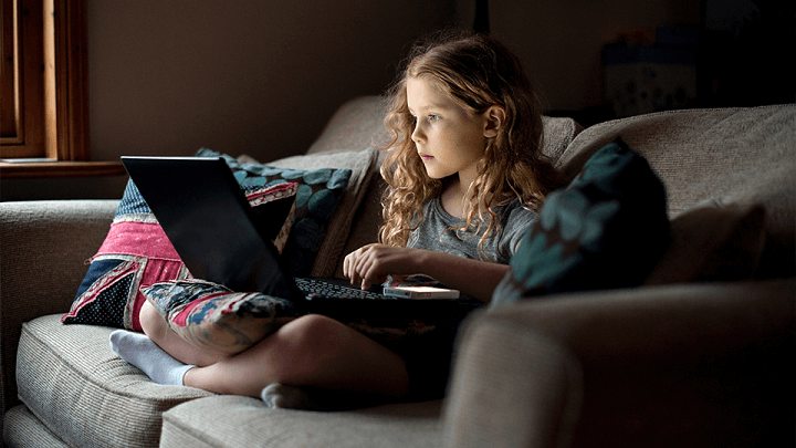 A young girl looking at a laptop