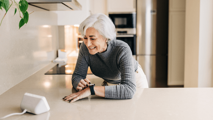 An elderly woman using her smart watch and smart technology in her kitchen