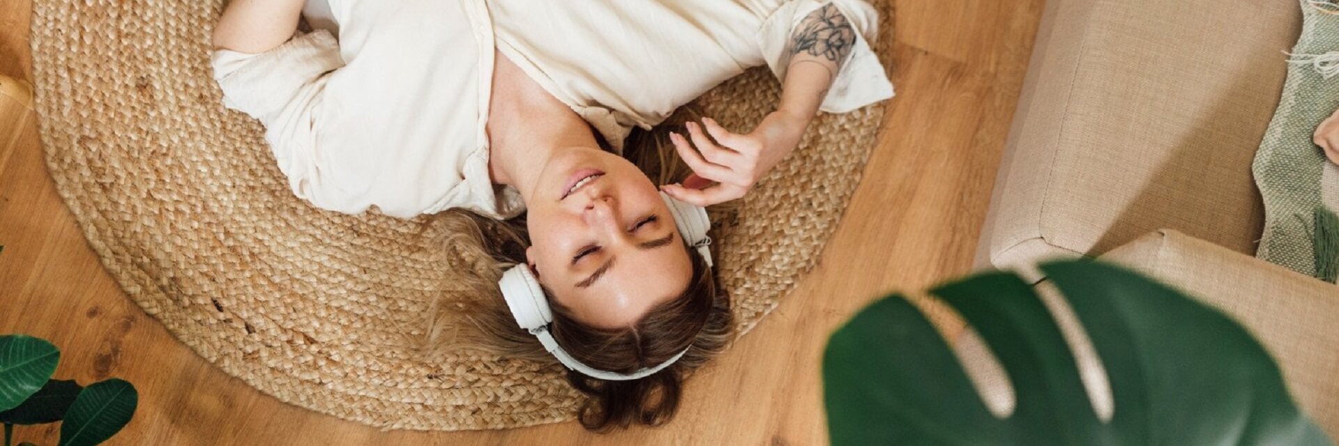 A woman lying on her back in her living room, with her headphones on