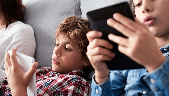 Two young boys using smart devices at home