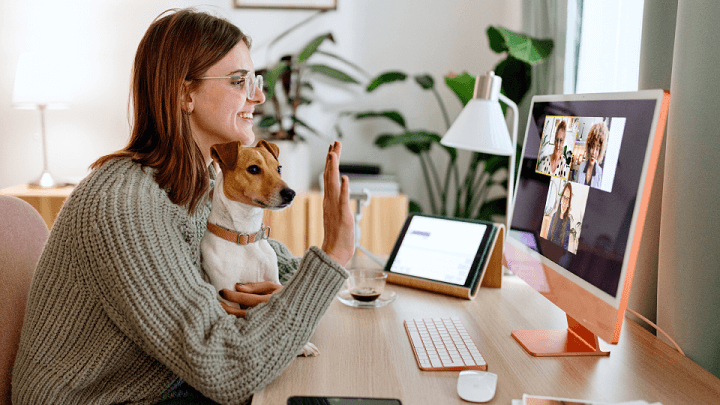 A woman on a work video call at home, with her dog on her lap